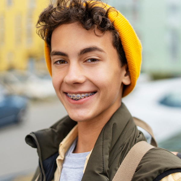 Eating with Braces – Tips for Enjoying Your Favorite Foods. A boy in a yellow hat is joyfully smiling on the street