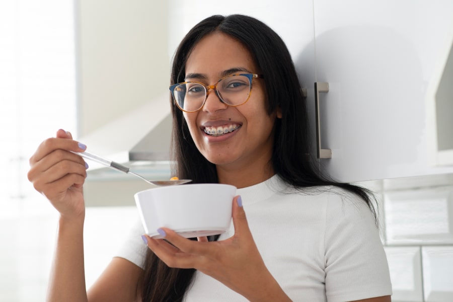 Braces-Friendly Foods – What You Can Enjoy with Your Braces. A girls is smiling while eating