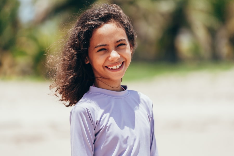 Is It Time for Your Child to See an Orthodontist? Here’s What to Look For! Young girl is joyfully smiling on the beach